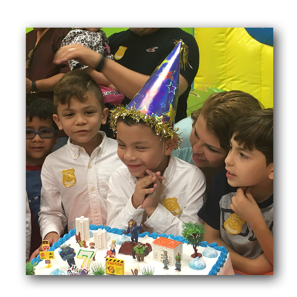 boy in party hat getting ready to blow out candles on cake